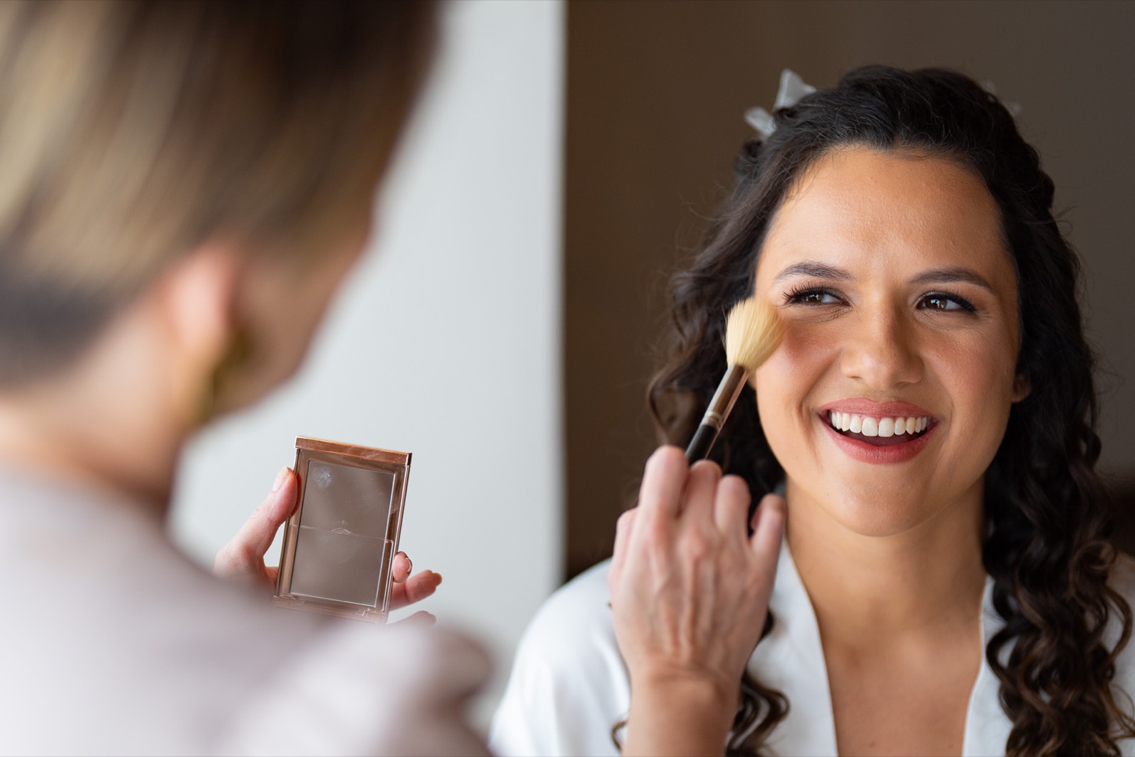 Noiva sorrindo durante a aplicação da maquiagem